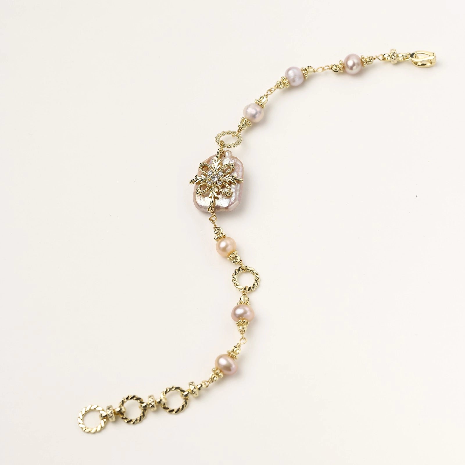 Gold-plated bracelet with pink baroque pearl centerpiece, floral connector, and freshwater pearls