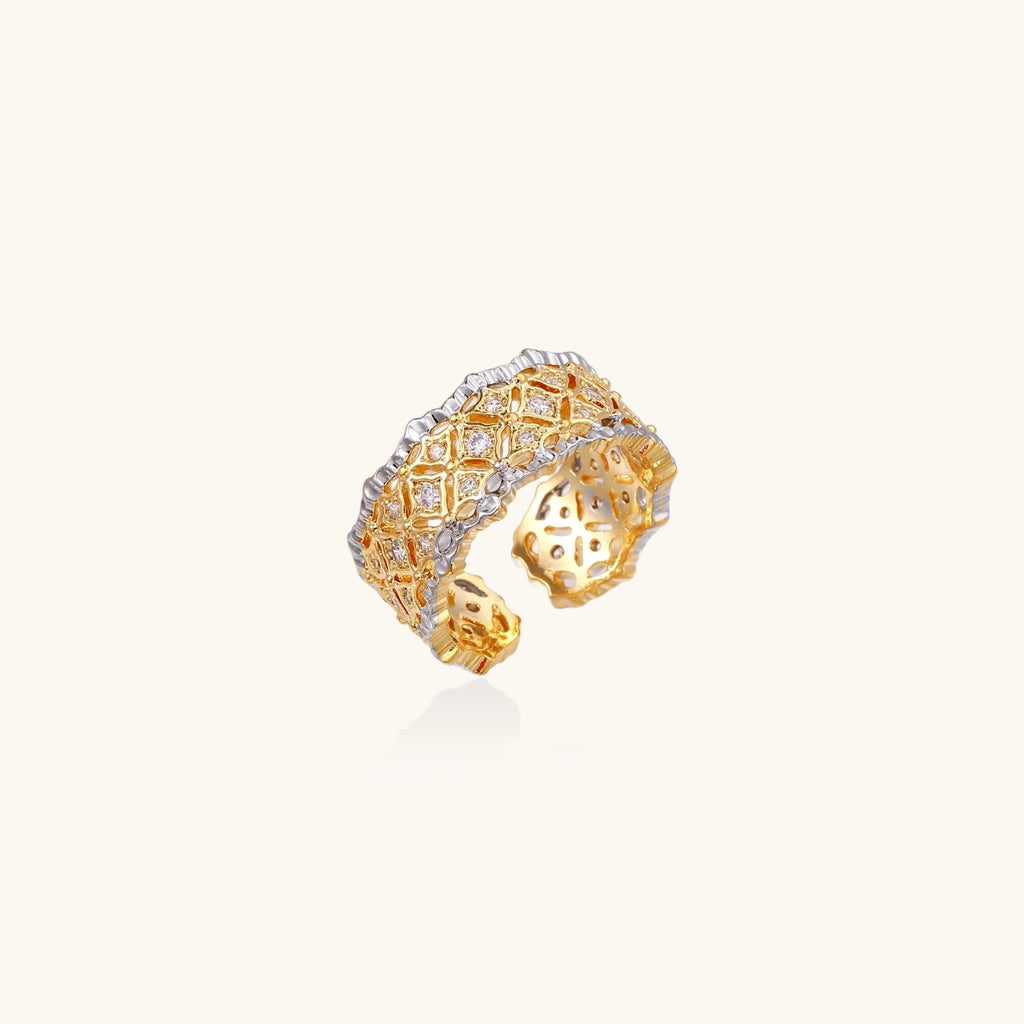 Two-tone ring with geometric lattice pattern in gold and silver finish with crystal accents on beige background