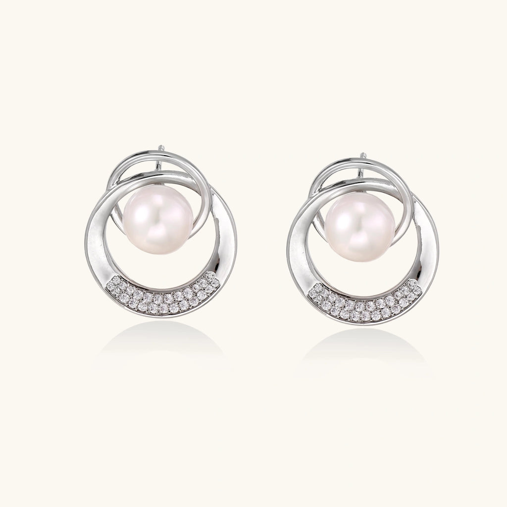 White gold-plated brass earrings with circular design, freshwater pearl center, and diamond accents