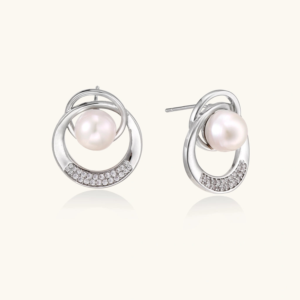 White gold-plated brass earrings with circular design, freshwater pearl center, and diamond accents