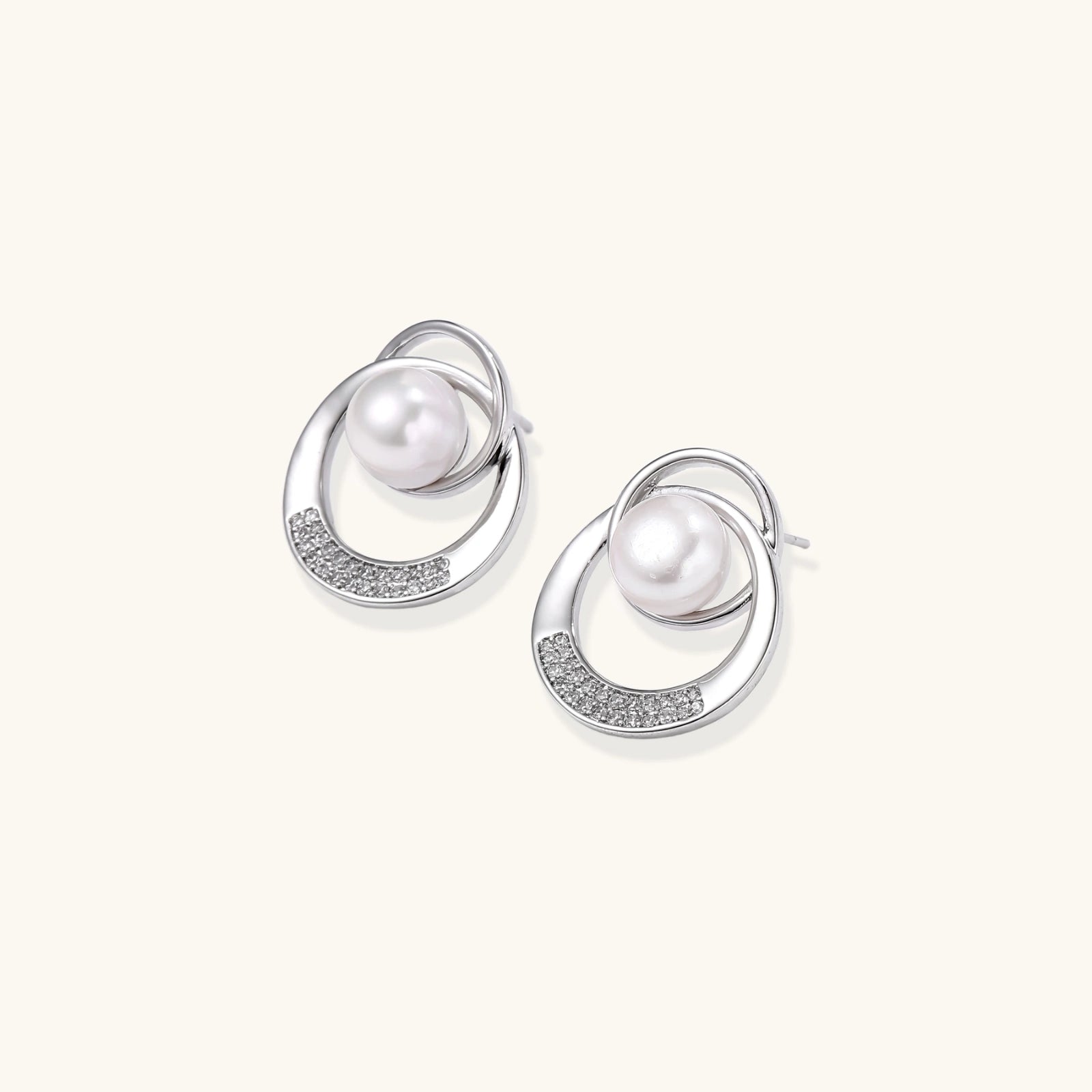 White gold-plated brass earrings with circular design, freshwater pearl center, and diamond accents